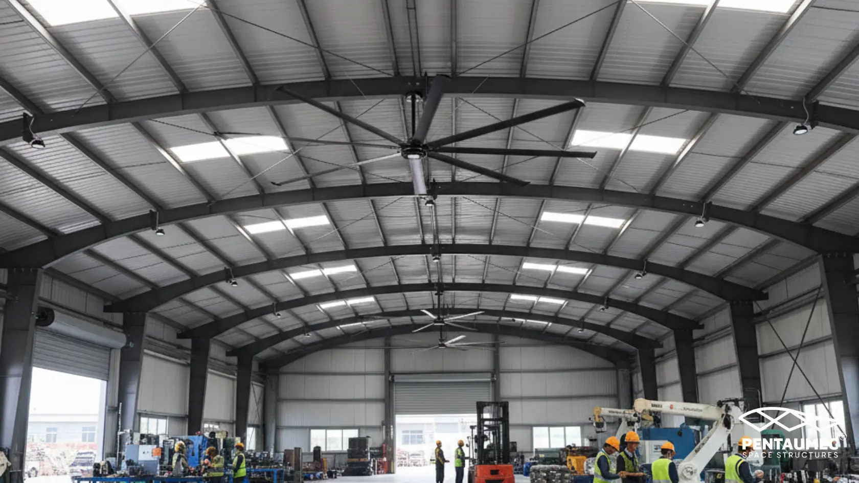 Interior of an Arch Type pre-engineered steel building showing continuous curved primary steel frames in rhythmic perspective with translucent roof panels and workers giving scale