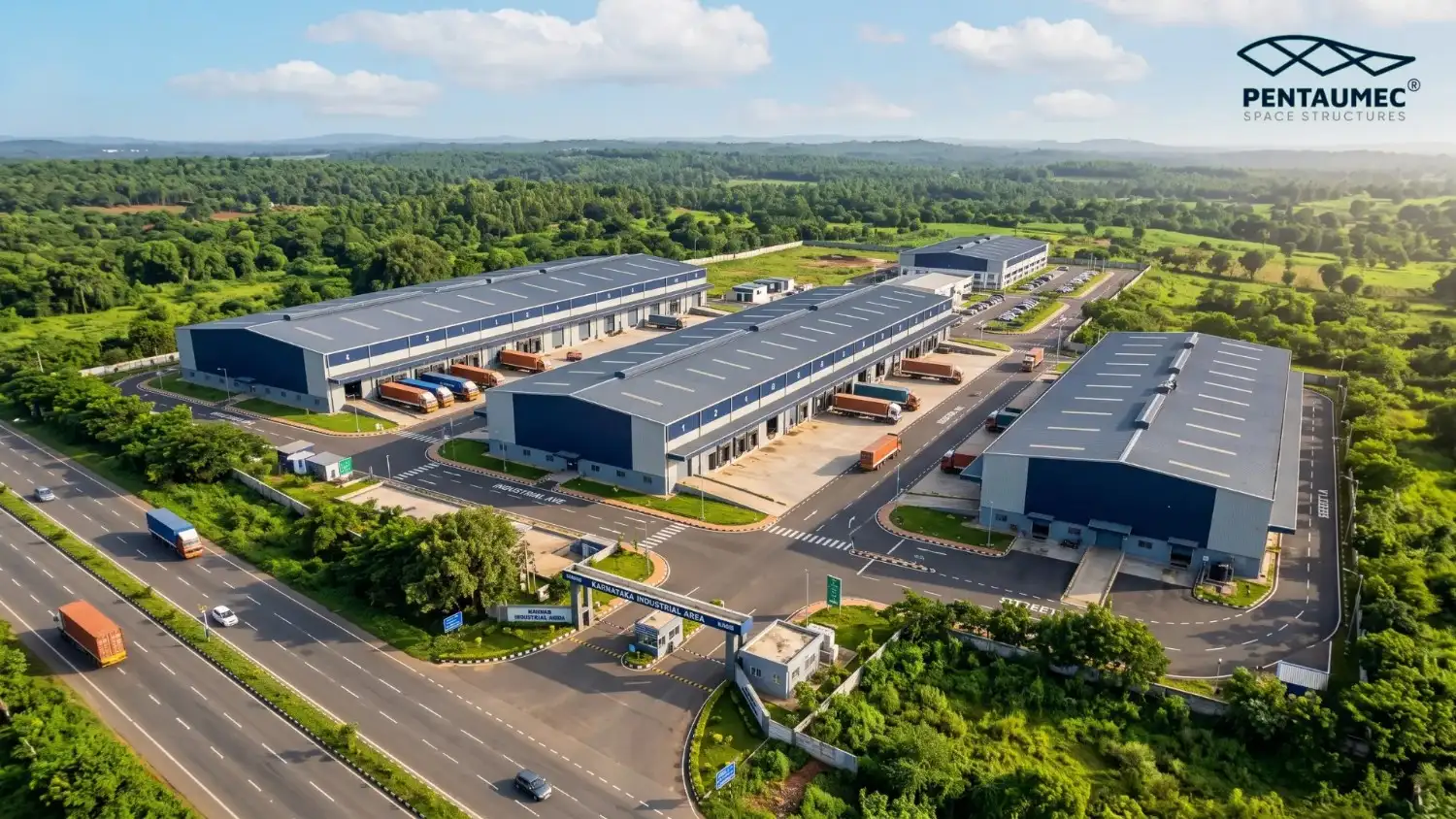 Aerial golden hour view of a completed PEB factory building complex in Karnataka with navy and grey cladding loading docks trucks solar panels and compound landscaping