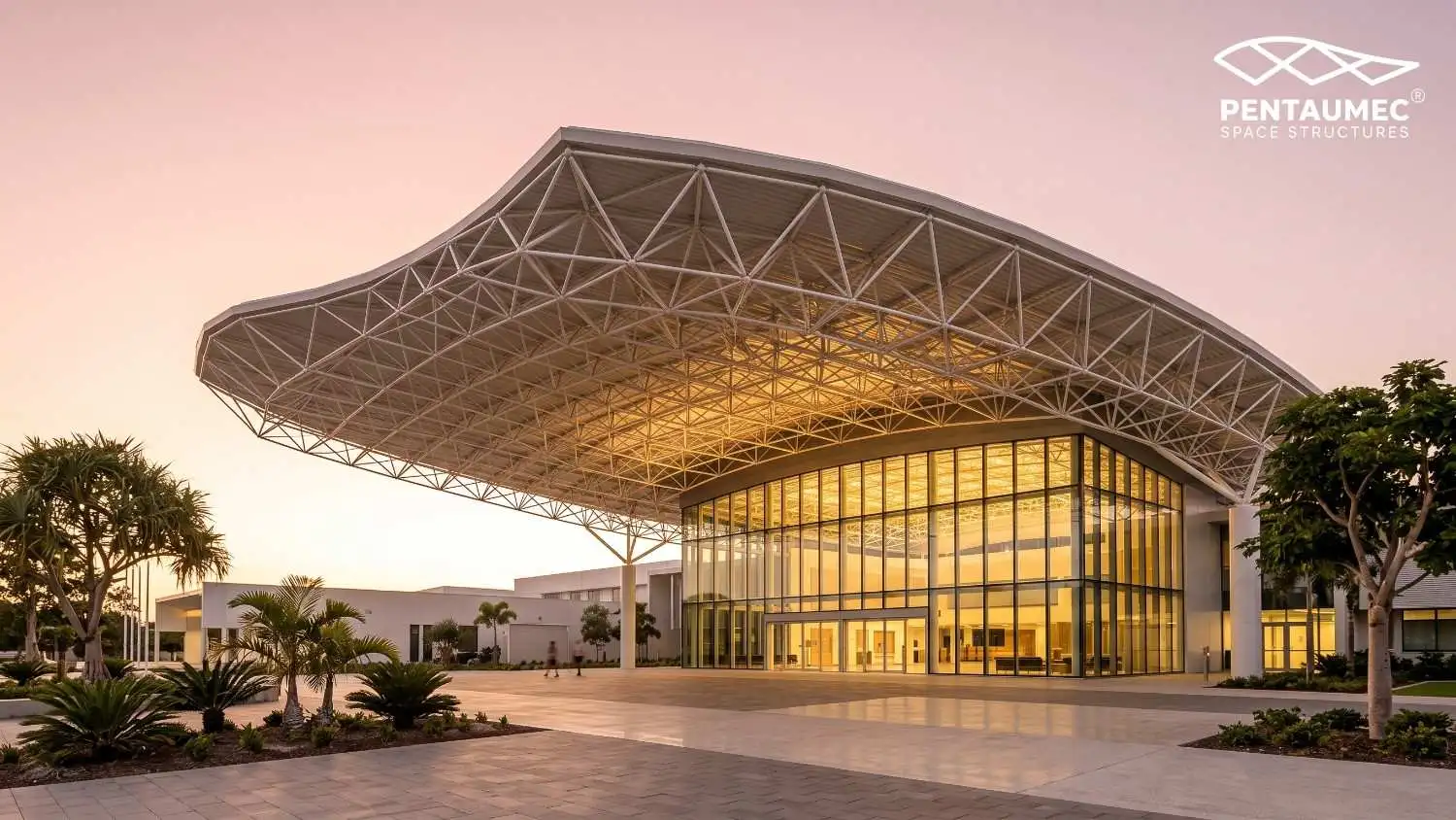 Completed building with a curved steel space frame canopy roof at golden hour